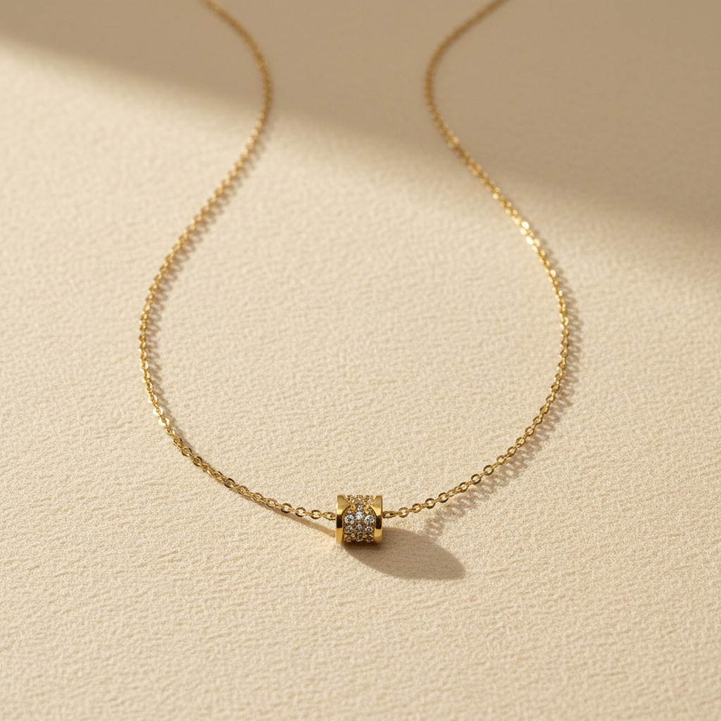 Gouden ketting met cilinder hangertje op crème achtergrond