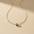 Gouden ketting met cilinder hangertje op crème achtergrond